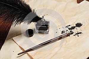 Inkwell with feather, fountain pen and vintage parchments on wooden table