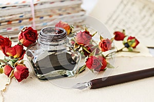 Inkwell, pen, dried roses and stack of vintage letters