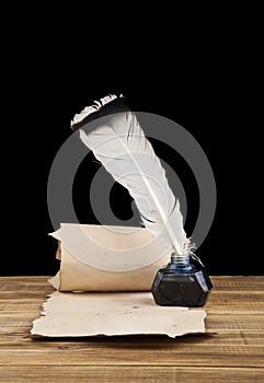 Inkwell with a pen and old paper on a black background