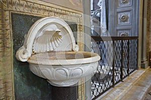 Inlaid marble holy water font and ancient romanesque church