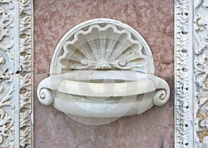 Inlaid marble holy water font outside an Italian Romanesque church - Santa Maria della Spina church (Italy-Pisa)