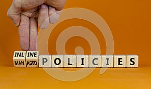 Inline or managed policies symbol. Businessman turns wooden cubes, changes words inline policies to managed policies. Orange