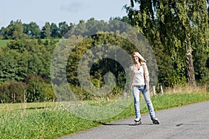 Inline skating young woman on sunny asphalt road