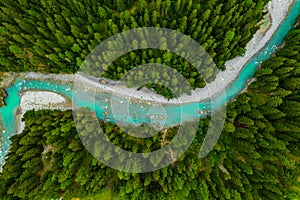 Inn River flowing in the forest in Switzerland. Aerial view from drone on a blue river in the mountains