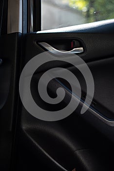 Inner car door handle of a compact SUV modern car, view from an interior of a back seat.