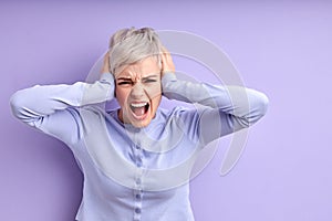 Inner pain. Devastated young caucasian woman closing ears with hands, screaming