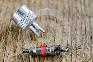 Inner tube valve on a wooden workshop table. Accessories for vulcanizer for repairing inner tubes and car tires.