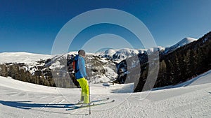 Innerkrems - A skiing man in blue and green outfit going down the ski run in Innerkrems, Austria. Everything is covered with snow