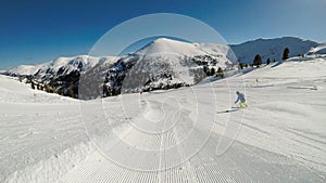 Innerkrems - A skiing man in blue and green outfit going down the ski run in Innerkrems, Austria. Everything is covered with snow