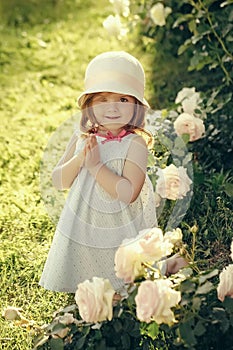 Innocence, purity and youth concept. Girl baby in hat smiling with praying hands in summer garden. Germination and