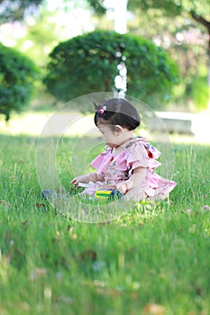 Innocent baby girl play a ball on the lawn