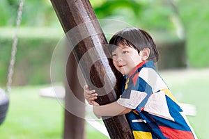 Innocent boy hugged the pole and made a cute face. Ragged child`s face. Children 2-3 years old. Happy baby wear colorful clothes.