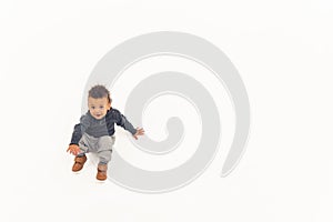 Innocent curious biracial baby boy standing up over white background. Copy space.