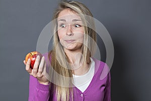 Innocent mesmerized 20s girl holding appetizing apple with envy