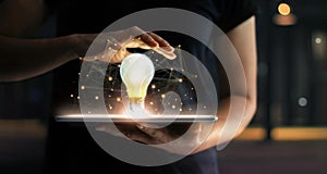 Innovation concept. Hands with tablet, illuminated lightbulb