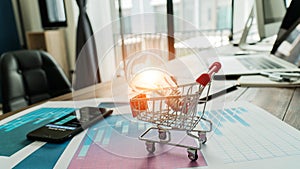 Innovation and inspiration concept,  abstract symbol. Light bulb glowing in shopping cart on business report sales data