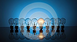 Innovation Standout: Single Illuminated Lightbulb Amidst Unlit Row for Leadership Concept photo