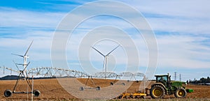 Innovative Agriculture: Green Tractor in Cultivated Field with Wind Turbines