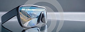 Innovative Augmented Reality Glasses Concept. A pair of black augmented reality glasses with a scenic mountain road