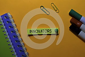 Innovators write on sticky notes. Isolated on orange table background