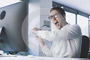 Insane angry businessman hitting the computer with the keyboard