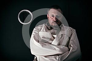 Insane man in a cell wearing a straitjacket