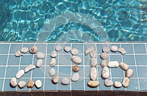 The inscription 2016 is laid out by pebble on a pool side