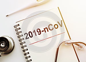 Inscription 2019-nCoV in notebook thermometre and stethoscope. Novel coronavirus outbreak. 2019-nCoV