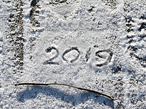 Inscription 2019 on the snow. The inscription and twig on the snow.