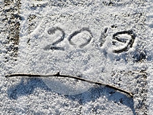 Inscription 2019 on the snow. The inscription and twig on the snow.