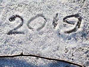 Inscription 2019 on the snow. The inscription and twig on the snow.