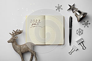 Inscription 2022 Goals written in planner and Christmas decor on white background, flat lay. New Year aims