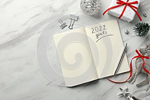 Inscription 2022 Goals written in planner and Christmas decor on white marble background, flat lay. New Year aims