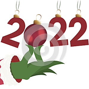 Inscription 2022, Hand of the grinch, the grinch holds a Christmas tree decoration, numbers 2022