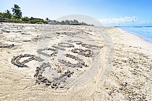 Inscription Adios Cuba on the sandy beach and sea water. translated from Spanish goodbye Cuba.