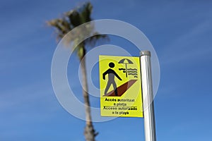 the inscription allowed access to the beach on a yellow sign in Spanish and Catalan acceso autoritzat a la playa