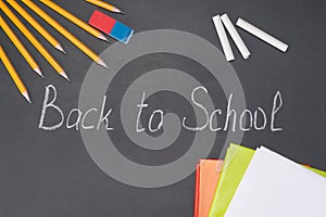 The inscription `back to school` is written in chalk on a blackboard among the stationery