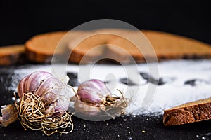 Inscription bakery on white wheat flour scattered Sliced rye bread with garlic on dark background