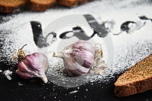 Inscription bakery on white wheat flour scattered Sliced rye bread with garlic on dark background