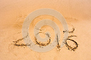 Inscription 2015 and 2016 on a beach sand, the wave is starting to cover the digits 2015