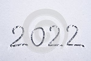 The inscription about the beginning of the new year 2022, the numbers are drawn on the snow in the winter season