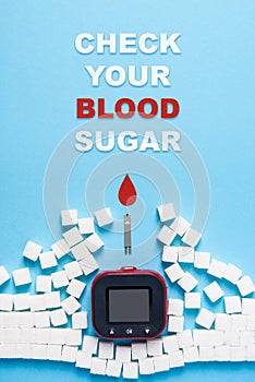 Inscription check your blood sugar, red blood drop, wall made of sugar cubes ruined by Glucose meter on blue background