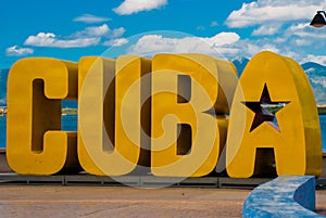 The inscription of the CUBA. Huge letters on the waterfront, against a blue sky with clouds in Santiago de Cuba.