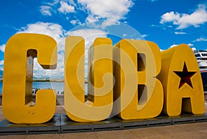 The inscription of the CUBA. Huge letters on the waterfront, against a blue sky with clouds in Santiago de Cuba.