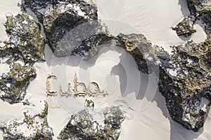 Inscription cube on the dense sand of the beach.