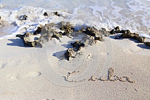 Inscription cube on the dense sand of the beach.