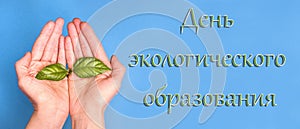 The inscription Day of environmental education in Russian on a blue background with hands with a green sprout, background baner