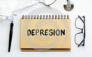 Inscription - DEPRESION. Written in a notepad to remind you of what`s important. Top view of the table along with a stethoscope