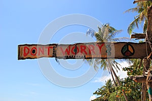 An inscription â€œDonâ€™t worryâ€ on the wooden abandoned hut on a sky background.