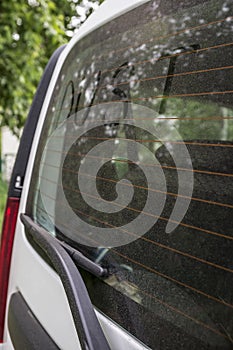 The inscription `dust` on the dirty rear window of the car.